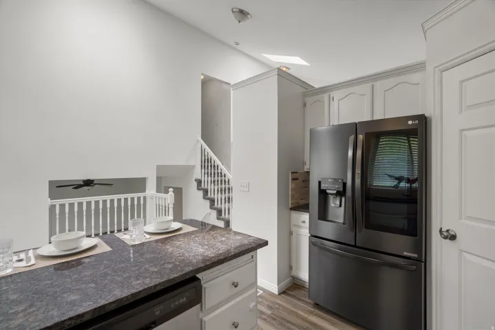 Kitchen featuring stainless steel appliances, light wood finished floors, a skylight, and white cabinets