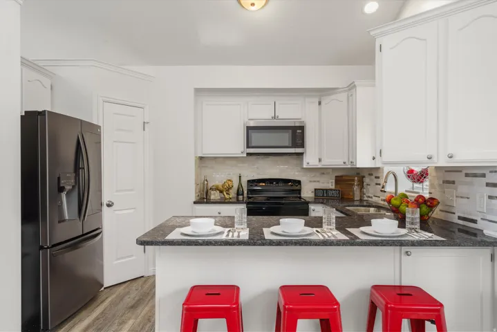 Kitchen with a peninsula, stainless steel appliances, white cabinets, and a kitchen breakfast bar