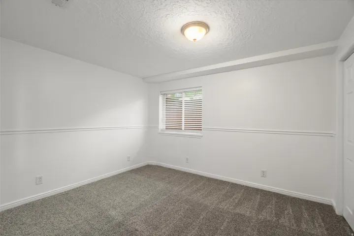 Unfurnished room with a textured ceiling and dark carpet