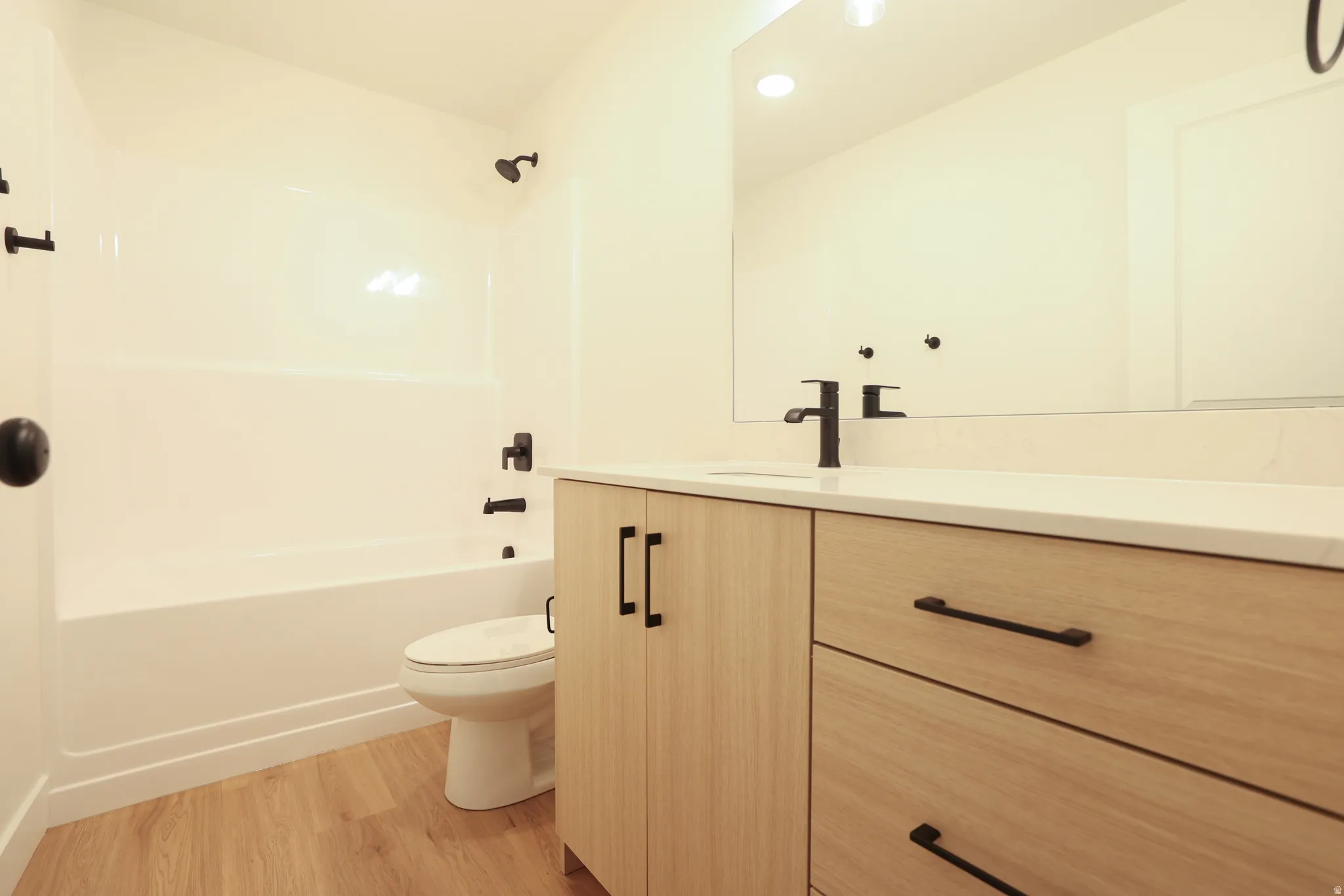 Full bath featuring vanity, light wood-style flooring, bathing tub / shower combination, and recessed lighting