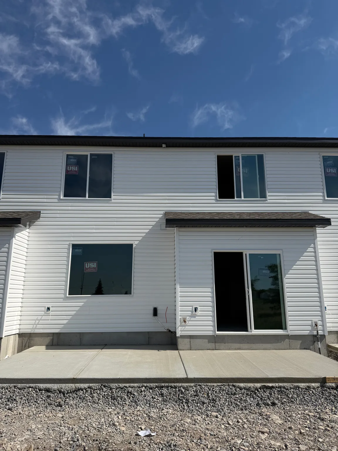 White vinyl siding exterior with an upper-level window and a lower-level window