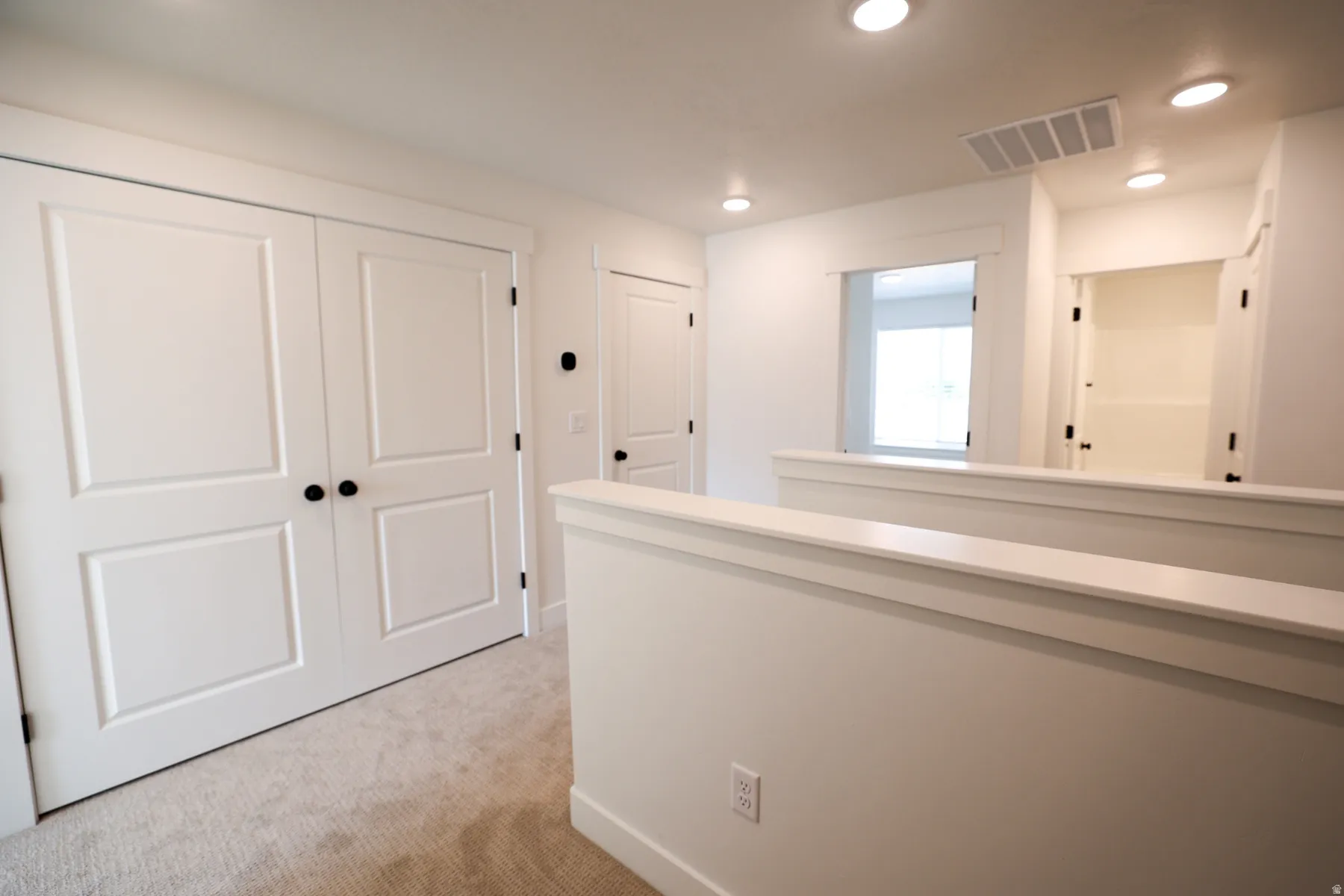 Hall featuring recessed lighting, light colored carpet, and an upstairs landing