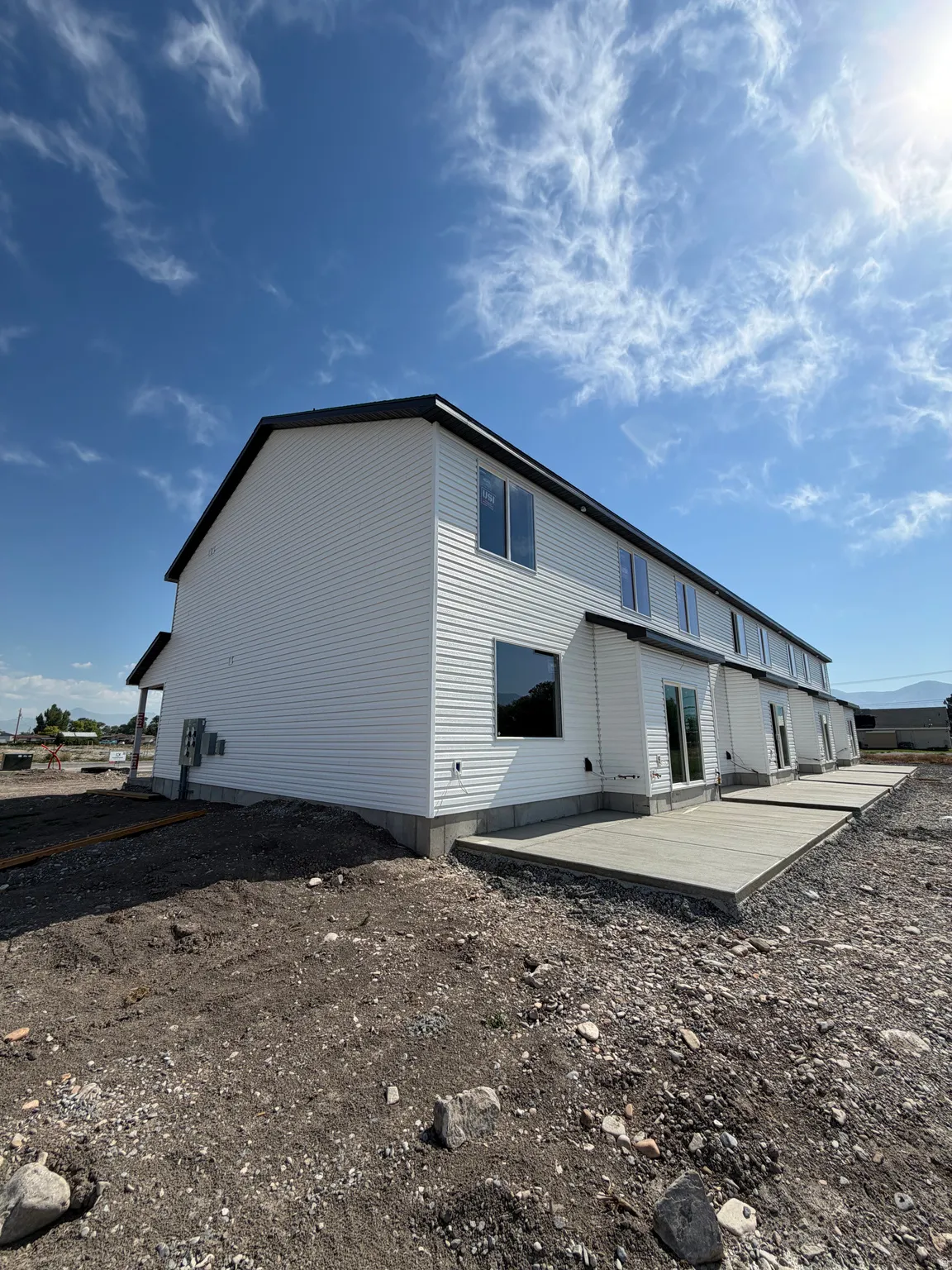 Modern two-story structure featuring white siding and a dark trim roofline