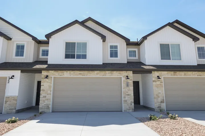 Contemporary exterior with vertical white siding, stone veneer accents, dark shingle roofing, and attached garage
