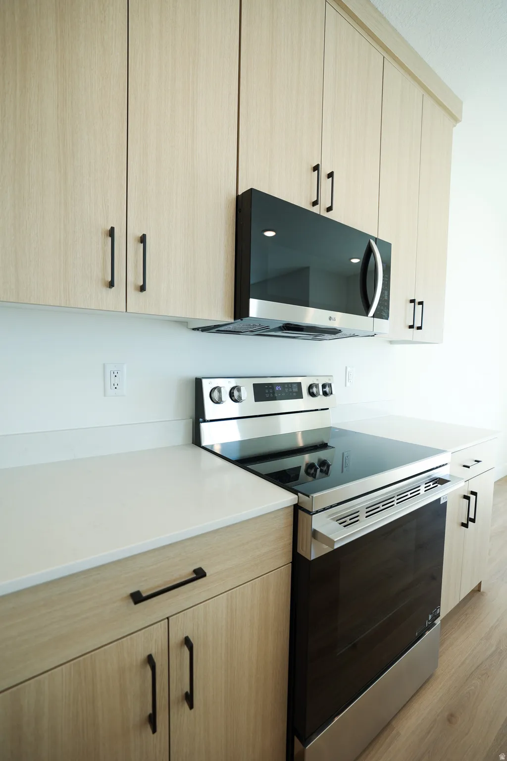Kitchen featuring light wood-finish cabinetry, stainless steel range, and an over-the-range microwave