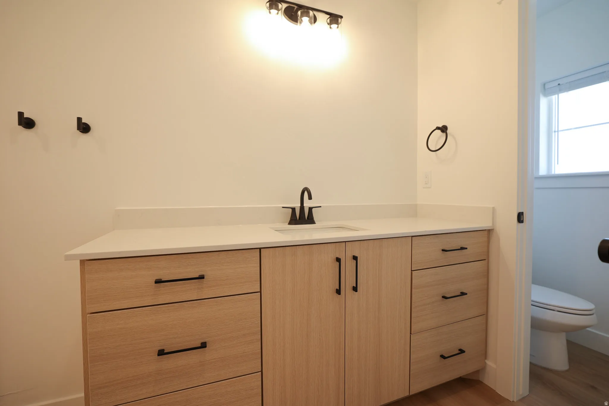 Wood-finish vanity with ample storage, integrated sink, and matte black fixtures