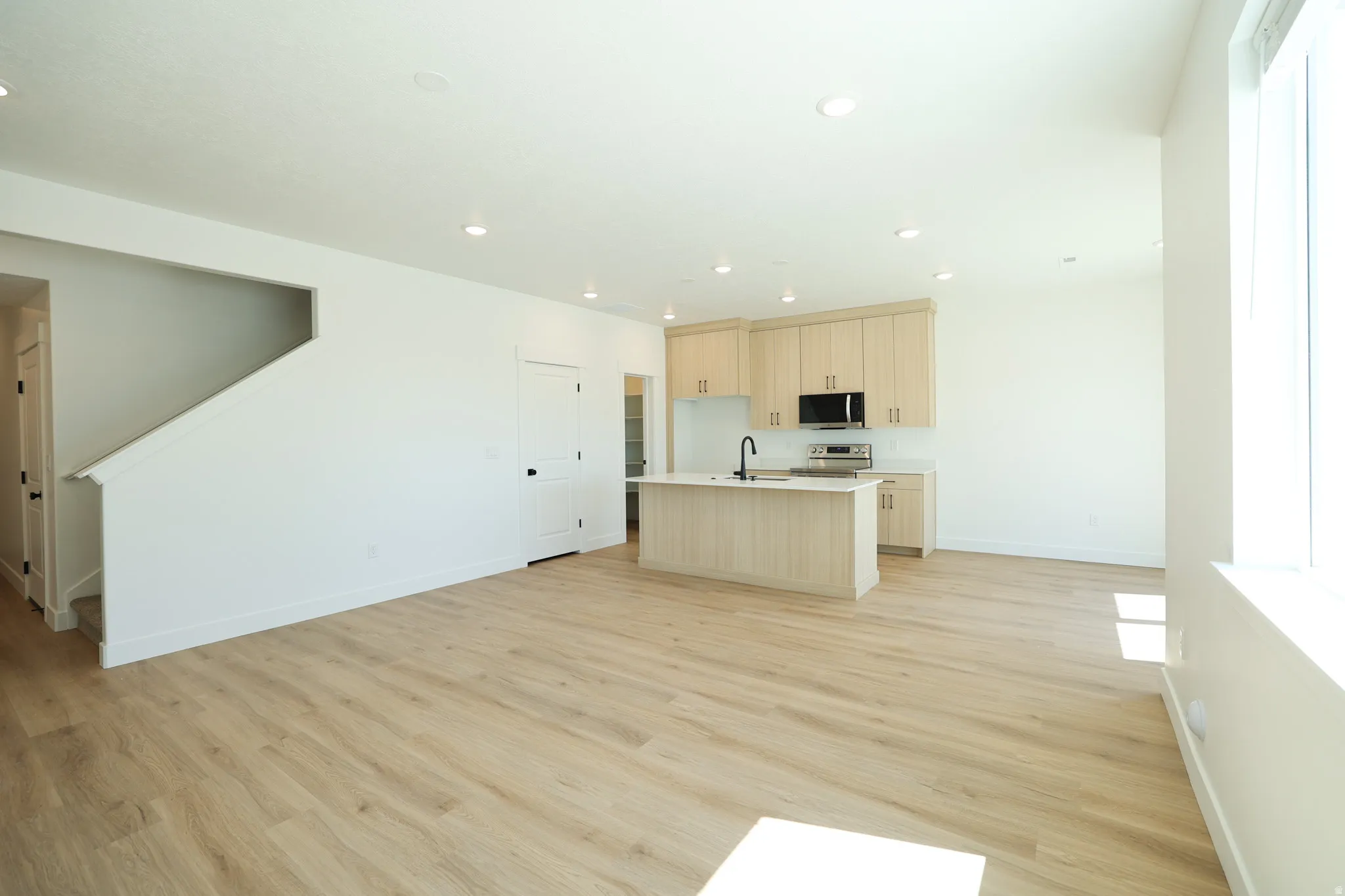 Open-concept living space with wood-finish flooring, recessed lighting, and a modern kitchen