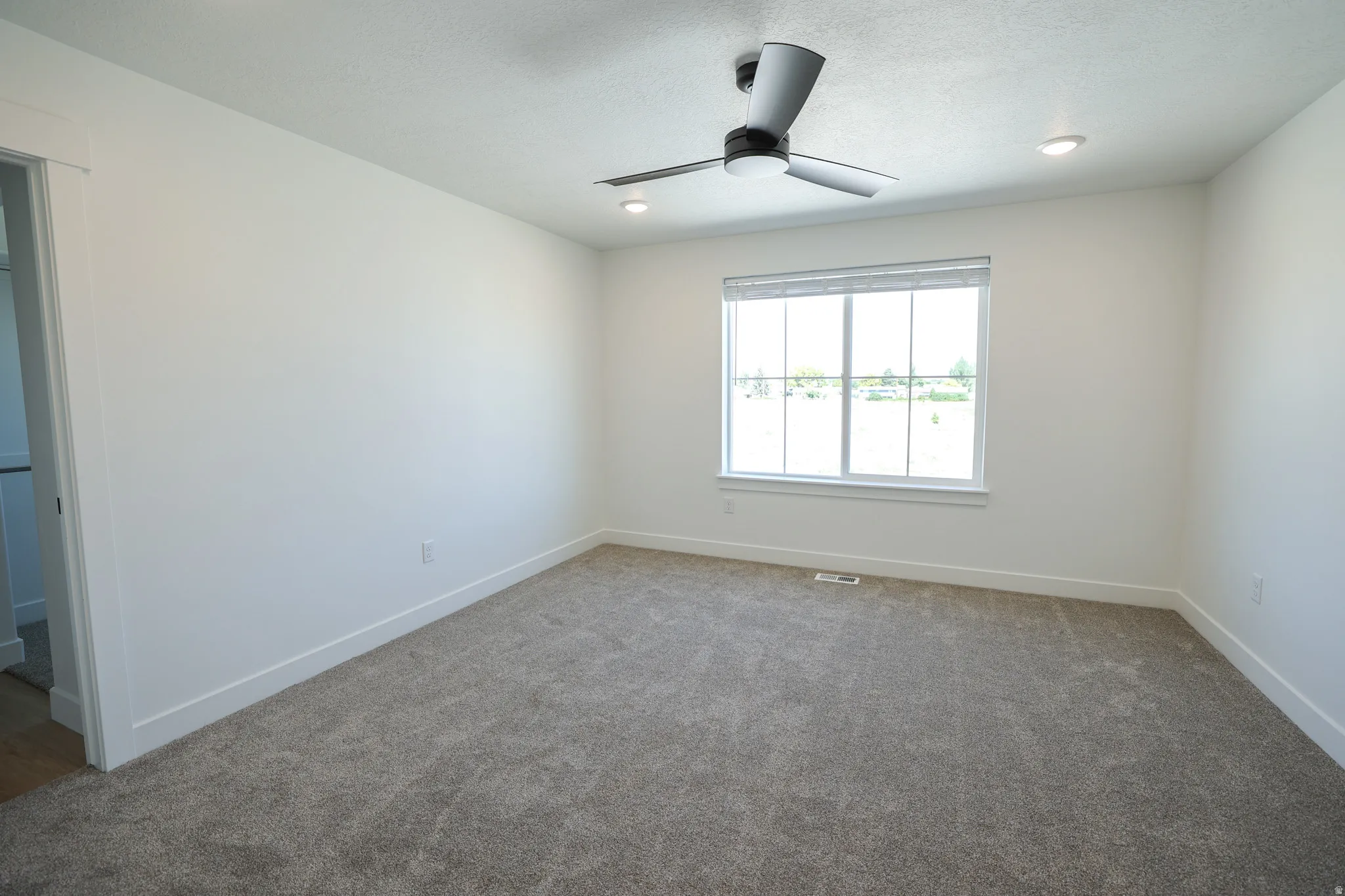 Recessed lighting, modern ceiling fan, large window with blinds, neutral carpeting, and white trim