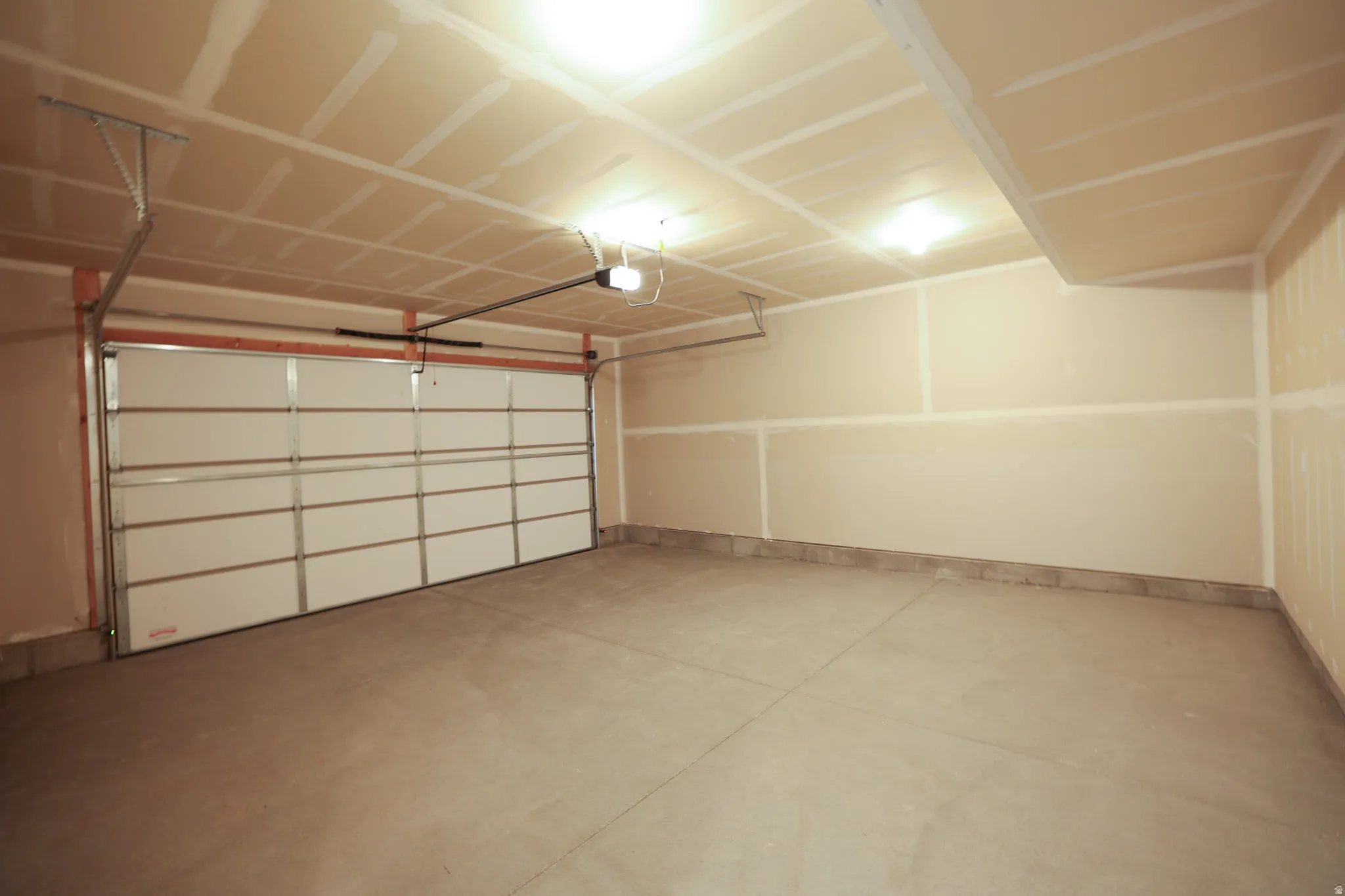 Attached garage with a sectional door, concrete flooring, and ceiling-mounted lighting