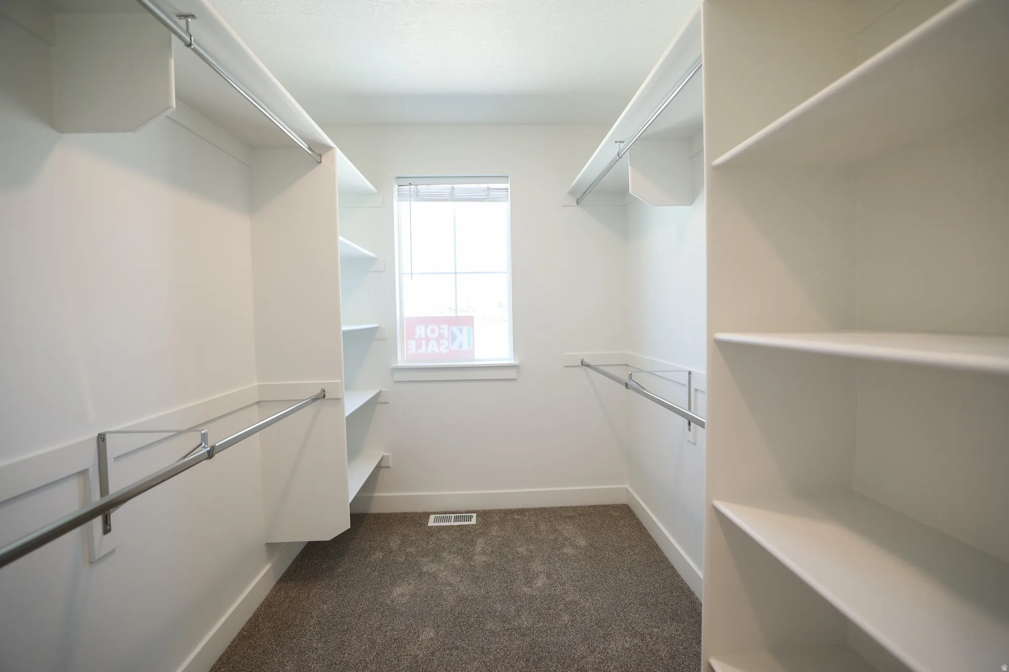 Walk-in closet with integrated shelving, multiple hanging rods, and a window for natural light