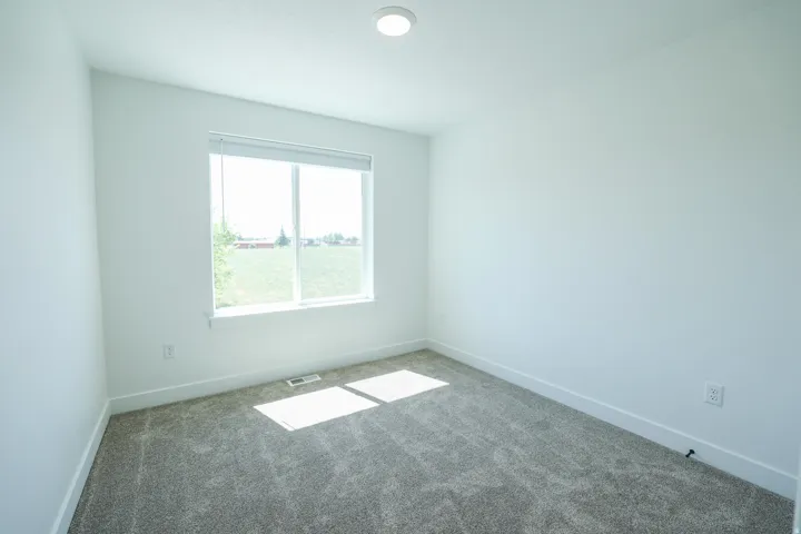 Carpeted room featuring a large window with blinds, recessed ceiling light, and white walls