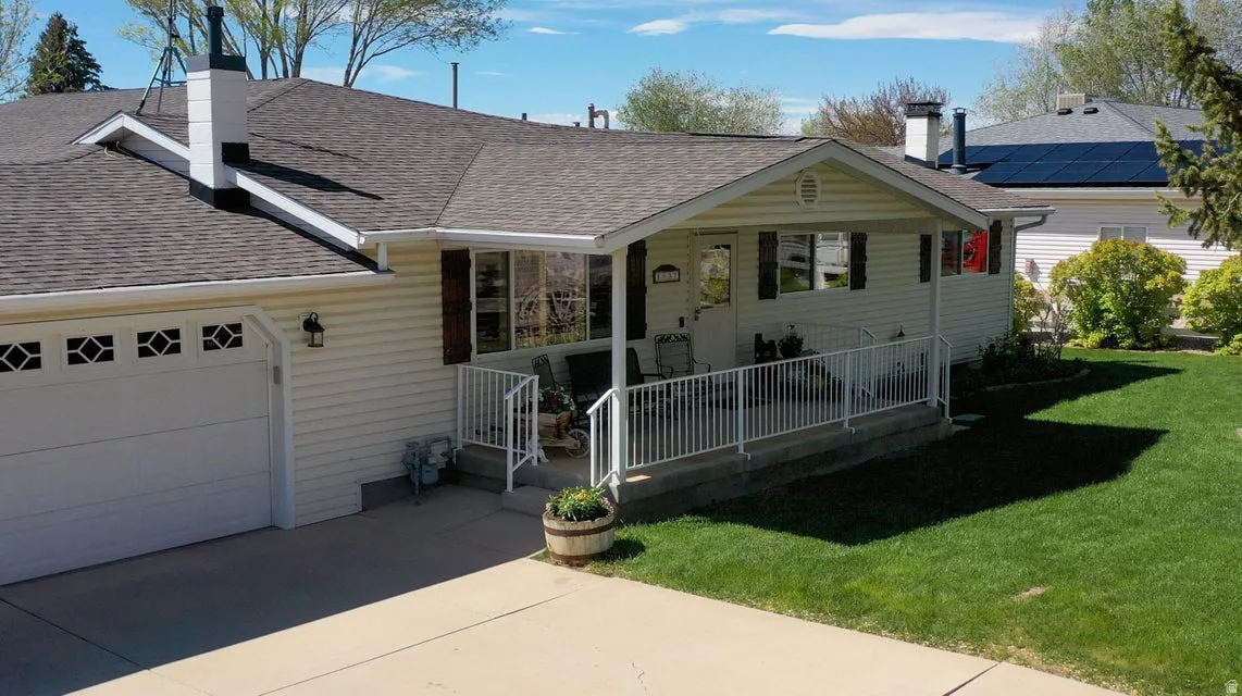 Single story home featuring roof with shingles, a front yard, a chimney, and covered porch