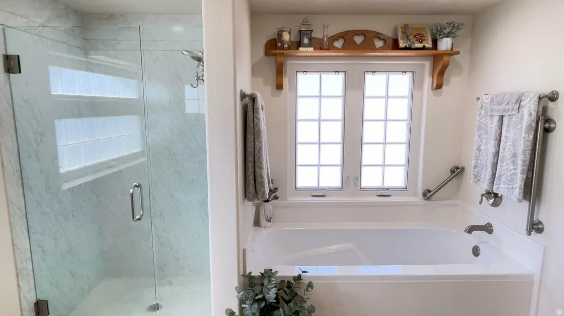 Bathroom with plenty of natural light, a garden tub, and a stall shower