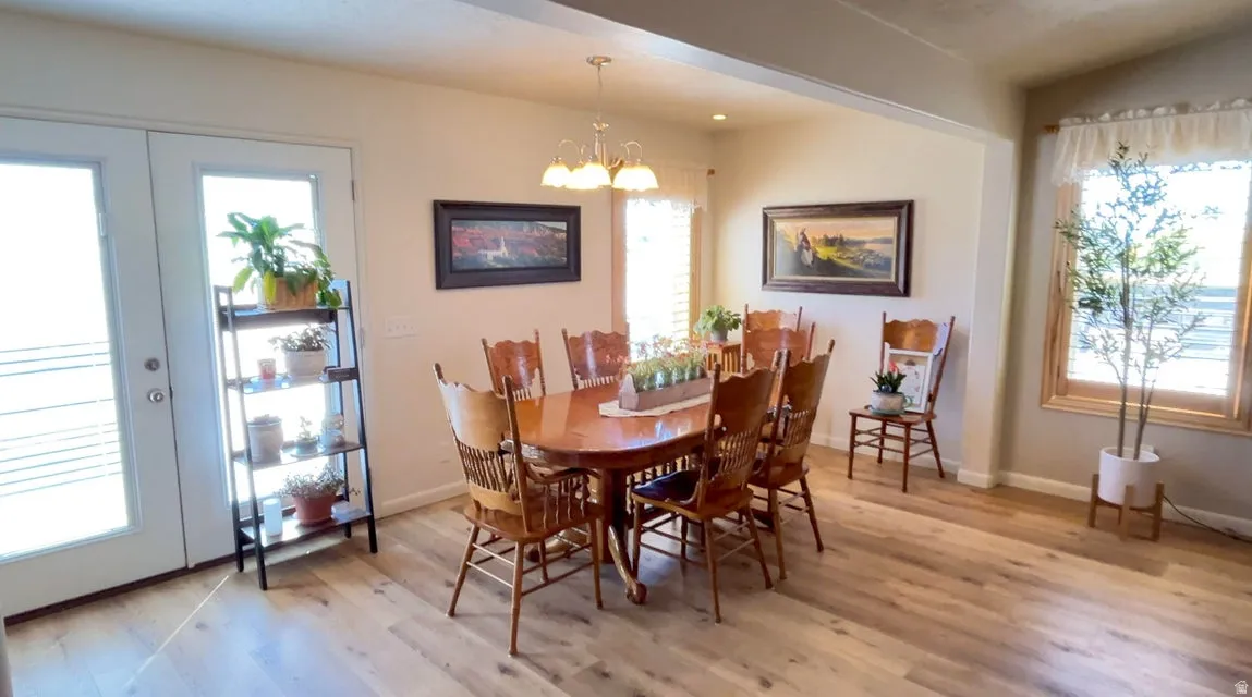 Dining space featuring healthy amount of natural light, light wood-type flooring, suspended lighting, vaulted ceiling, and french doors