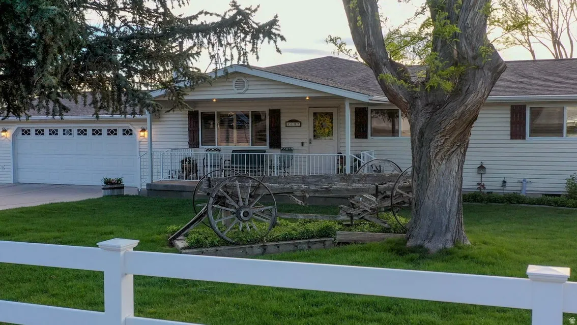 View of front of house with covered porch, a front lawn, an attached garage, and concrete driveway