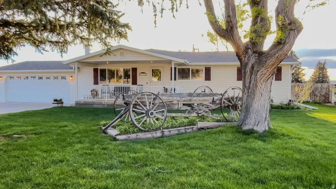 Ranch-style home featuring a porch, a front lawn, a garage, and driveway