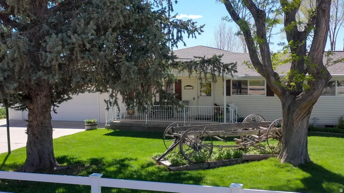 View of front facade with a shingled roof, a front yard, concrete driveway, and a garage