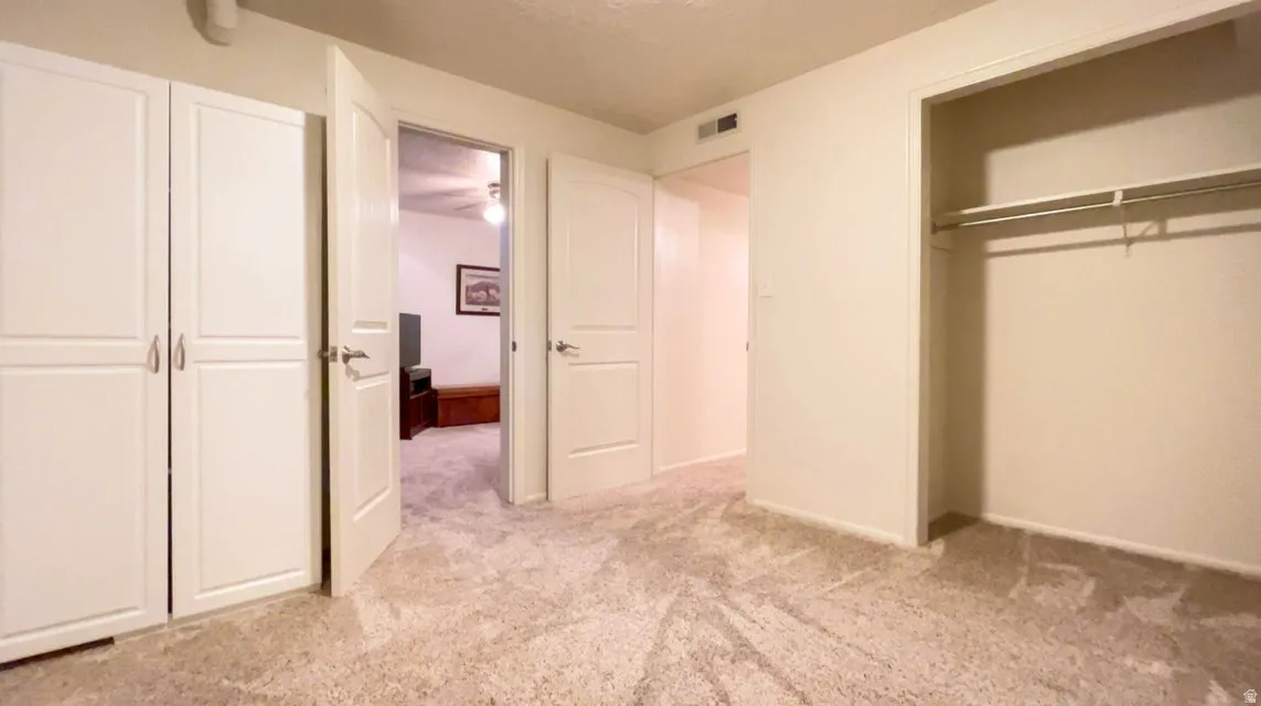Unfurnished bedroom with light carpet, a closet, and a textured ceiling