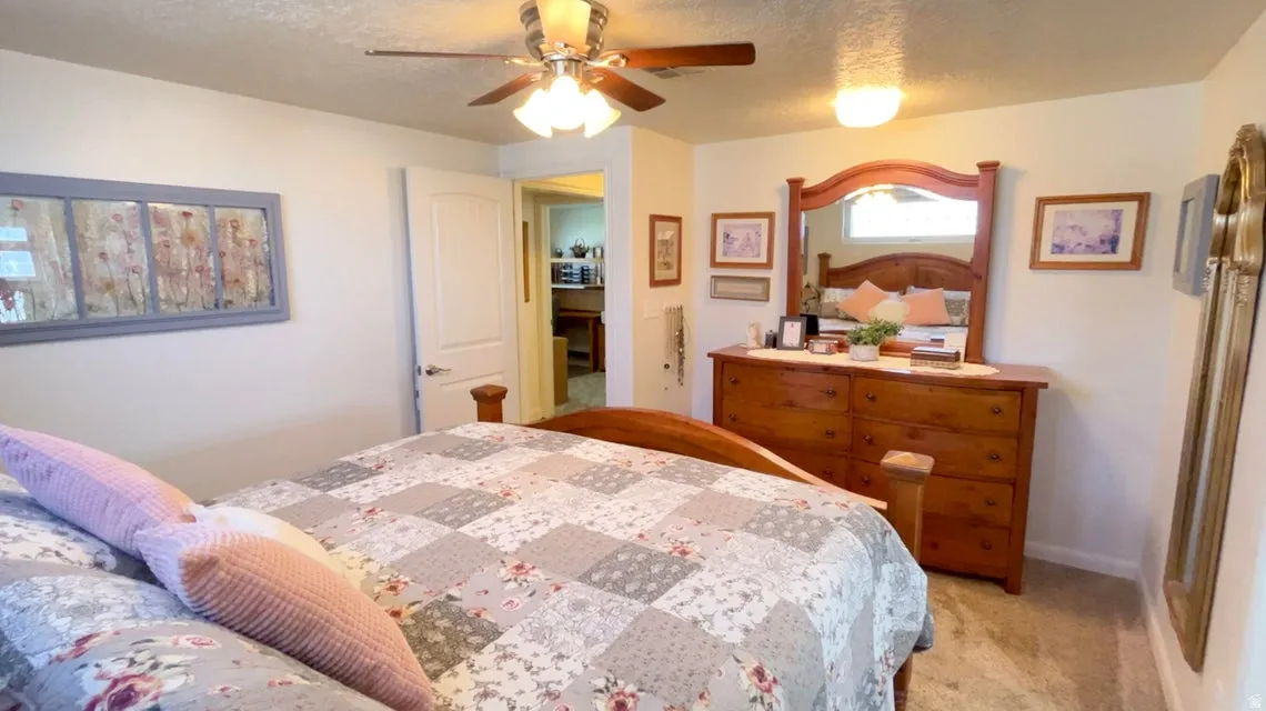 Bedroom featuring a textured ceiling, light colored carpet, and a ceiling fan