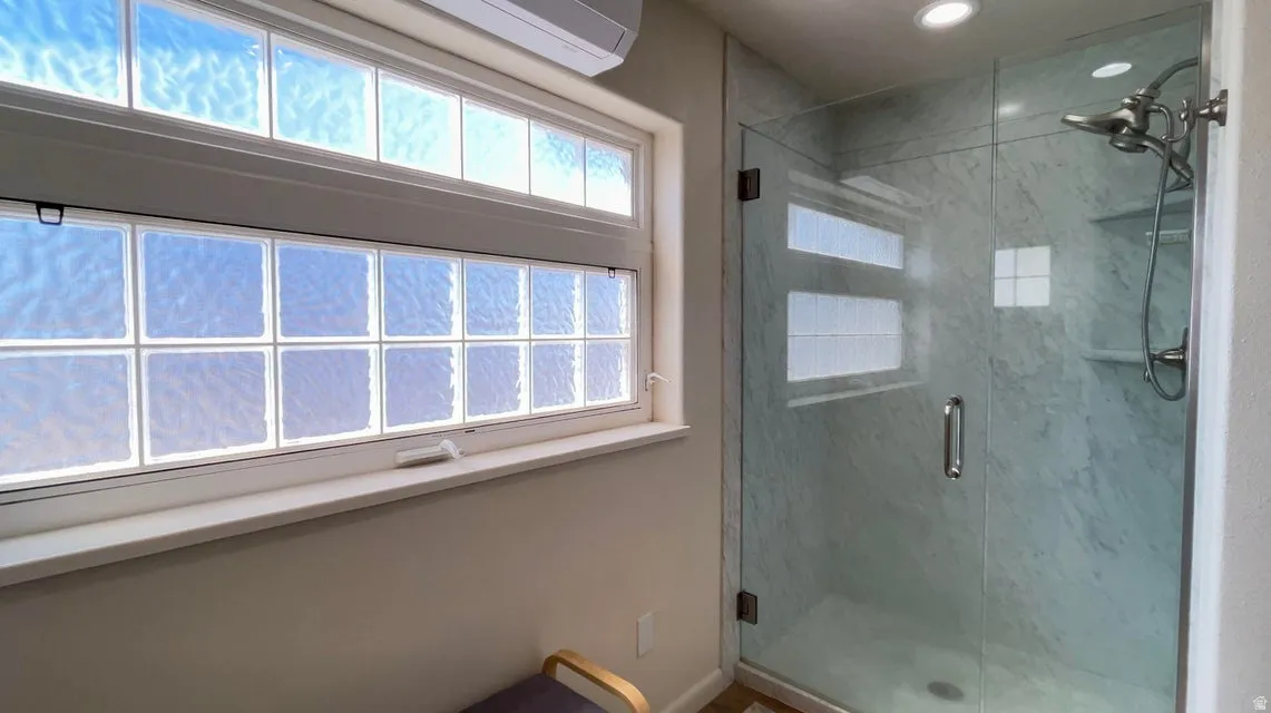 Full bath with a marble finish shower and a wall mounted mini split