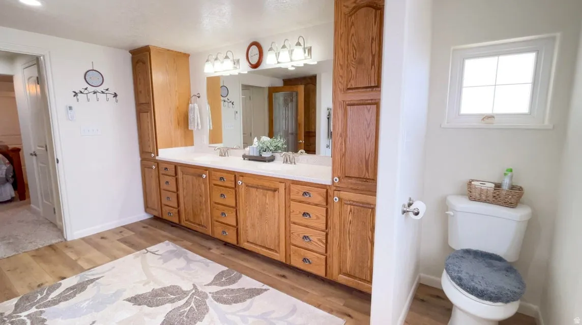 Full bath featuring vanity, light wood finished floors, and ensuite bath