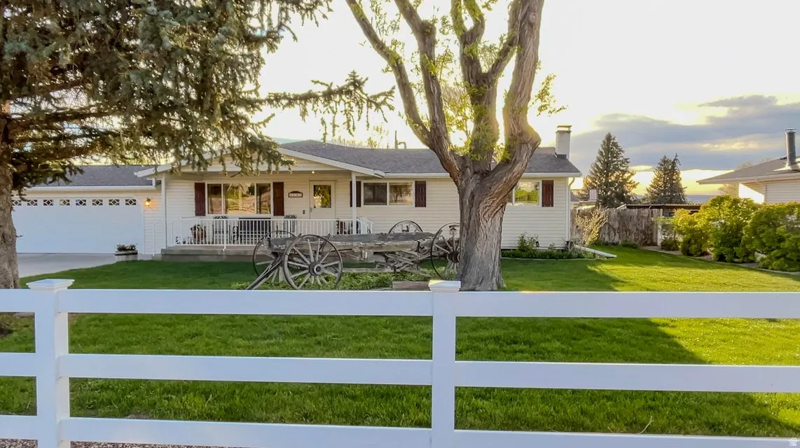 Single story home with a fenced front yard, an attached garage, a porch, concrete driveway, and a chimney