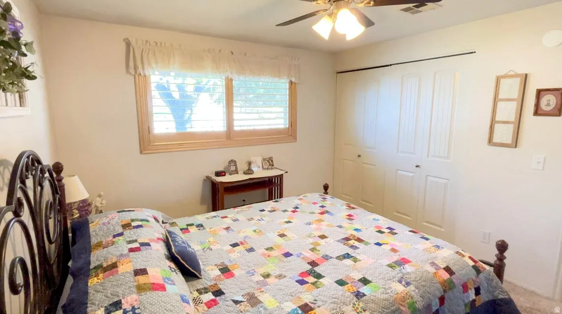 Bedroom featuring a ceiling fan, a closet, and carpet