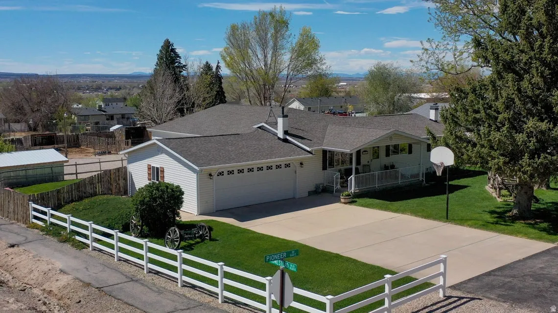 Ranch-style home featuring a fenced front yard, a shingled roof, concrete driveway, and a garage
