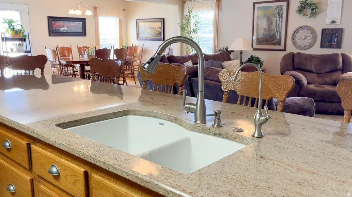 Kitchen featuring open floor plan, suspended lighting, light stone countertops, and healthy amount of natural light