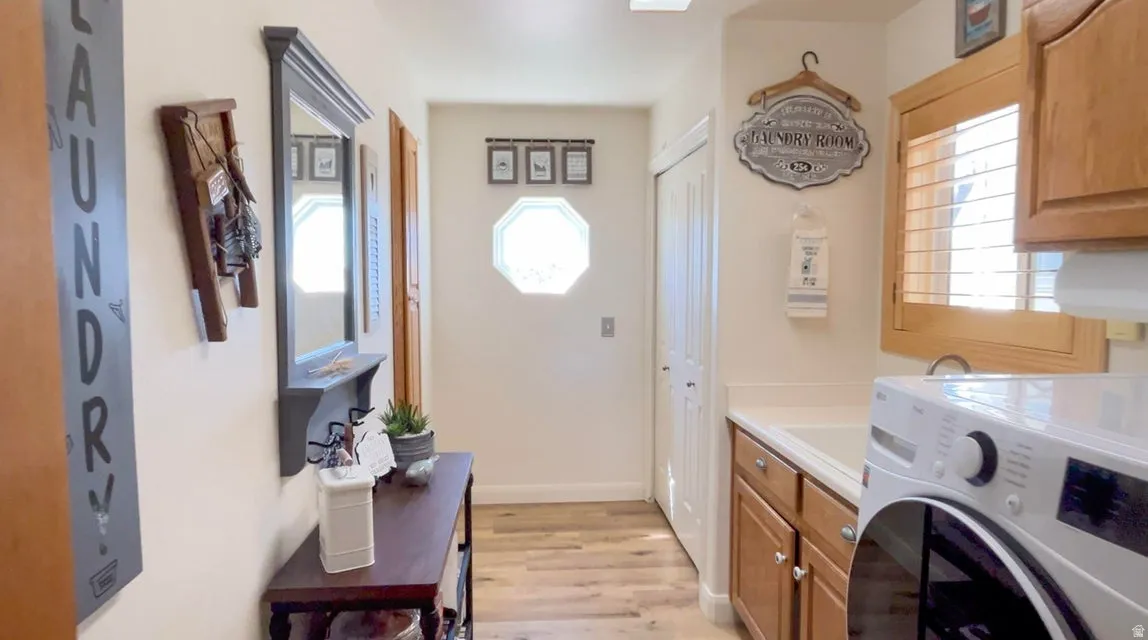 Laundry room featuring washer / dryer, cabinet space, and light wood finished floors