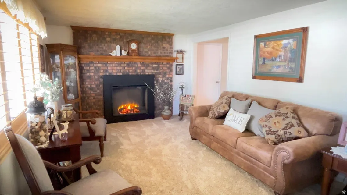 Carpeted living area featuring a brick fireplace