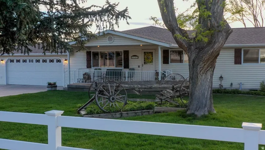 View of front of house with covered porch, a front lawn, an attached garage, and concrete driveway