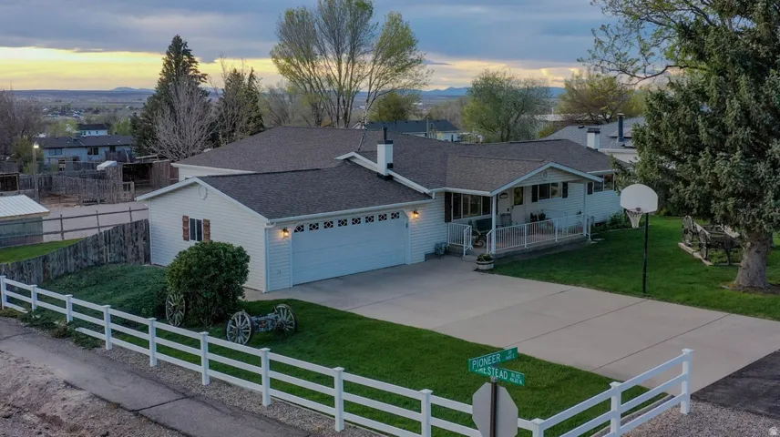 Single story home featuring a fenced front yard, a shingled roof, concrete driveway, and a garage