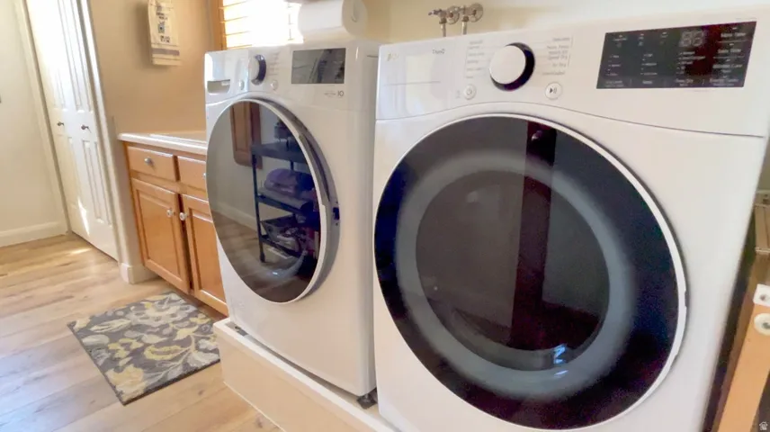 Laundry room featuring light wood-style flooring, washer and dryer, and cabinet space