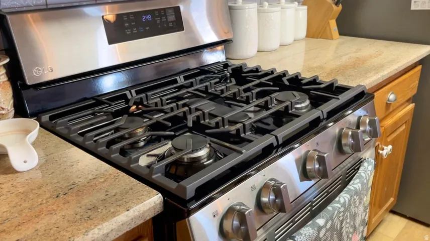 Kitchen view of stainless steel range with gas cooktop, light stone countertops, and wood finish cabinetry