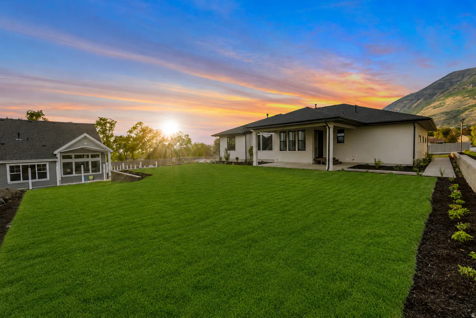 Expansive manicured lawn with a contemporary ranch-style residence and a separate gabled structure