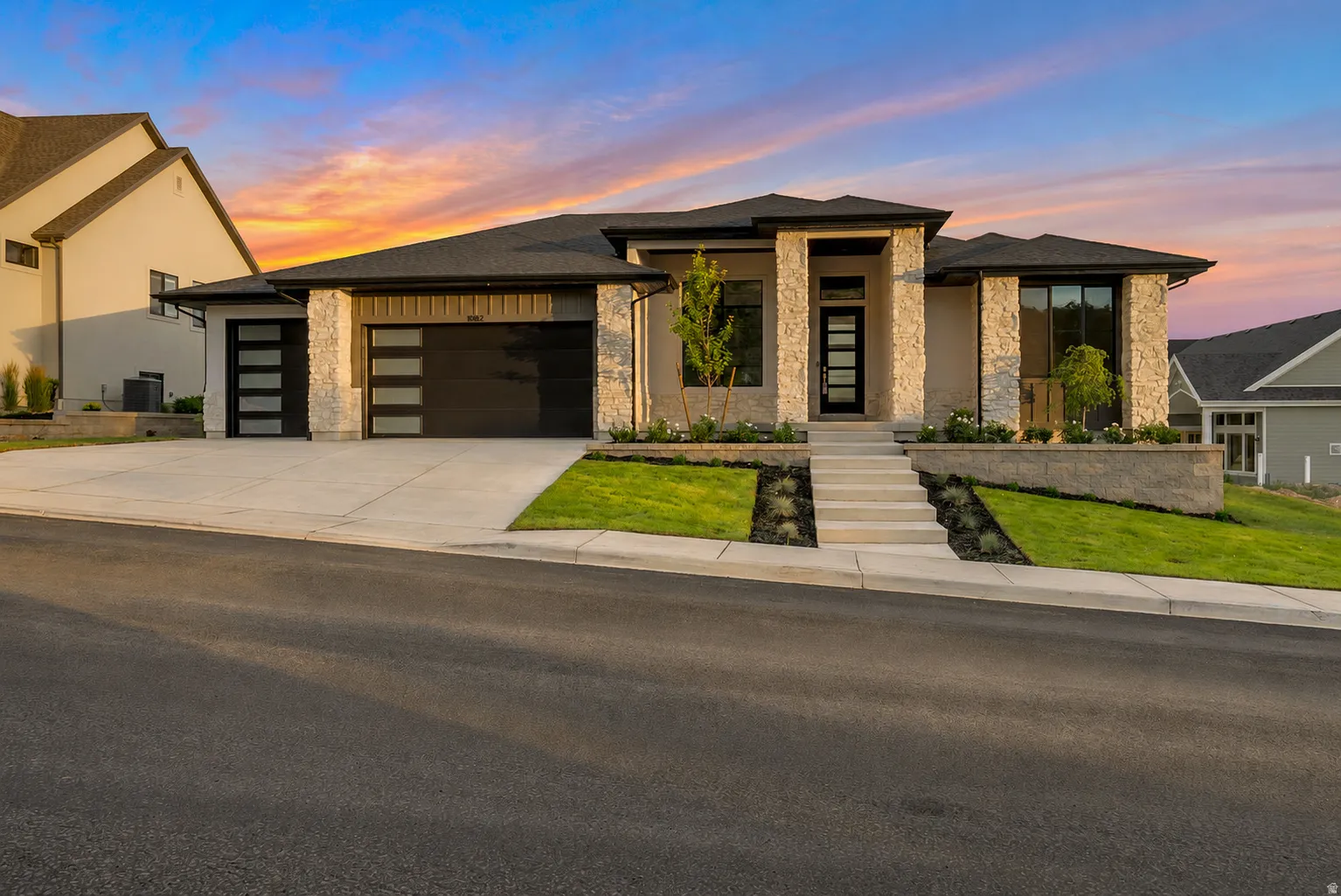 Contemporary home featuring a stone facade and a multi-car garage with modern glass-paneled doors