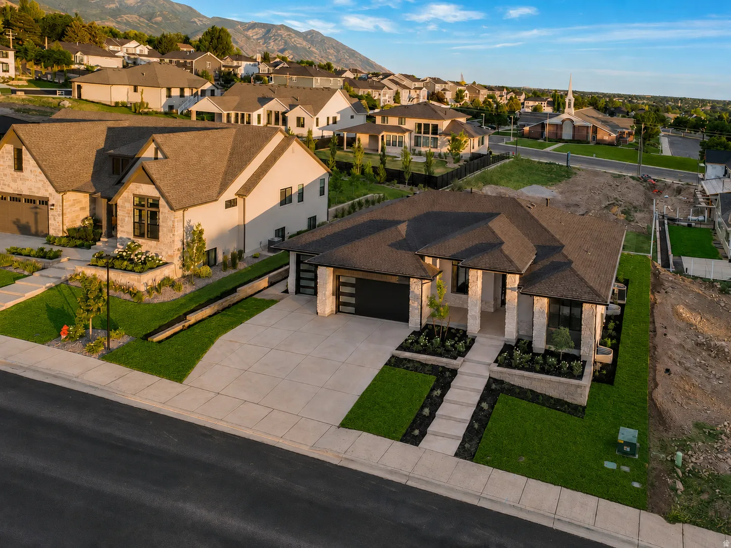 Modern ranch-style residence featuring a dark shingle roof, stone and stucco exterior, and a two-car garage