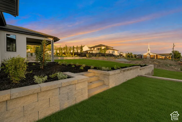 Spacious backyard featuring tiered landscaping with retaining walls, a manicured lawn, and planted garden beds