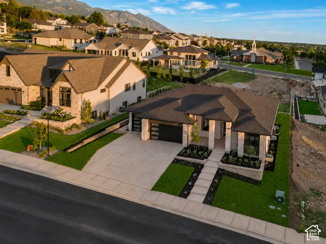 Modern ranch-style residence featuring a dark shingle roof, stone and stucco exterior, and a two-car garage