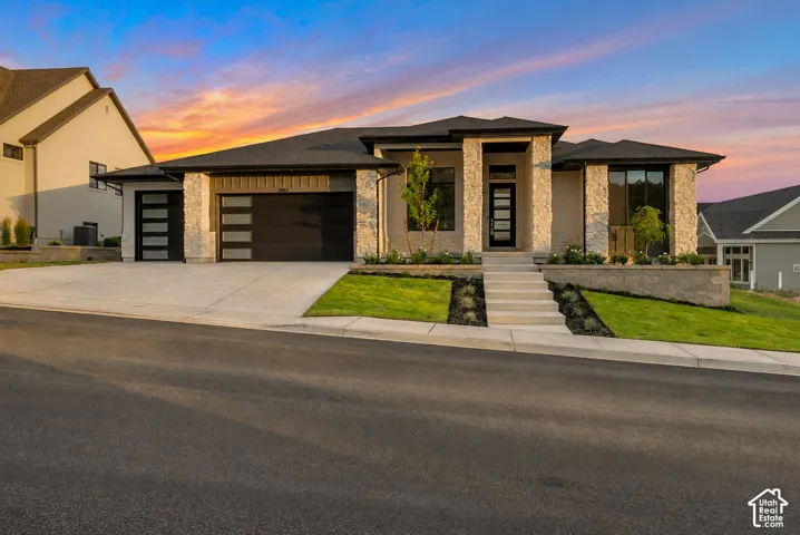 Contemporary home featuring a stone facade and a multi-car garage with modern glass-paneled doors