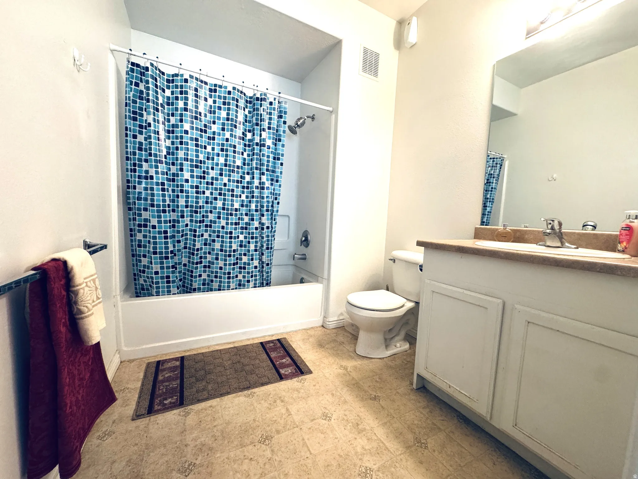 Bathroom featuring vanity, shower / tub combo, and light floors