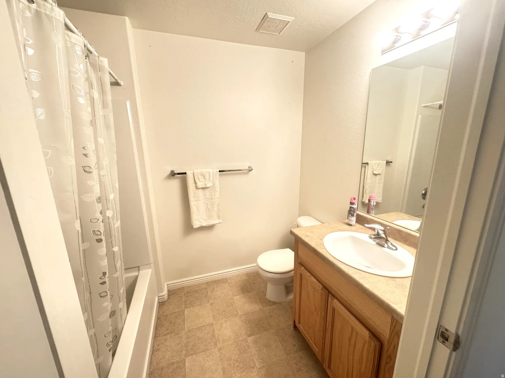 Bathroom with vanity, a textured ceiling, and shower / tub combo