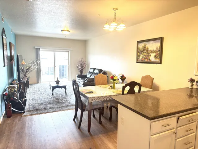 Kitchen, dining area and gathering room featuring light wood-style flooring, a textured ceiling, and a chandelier