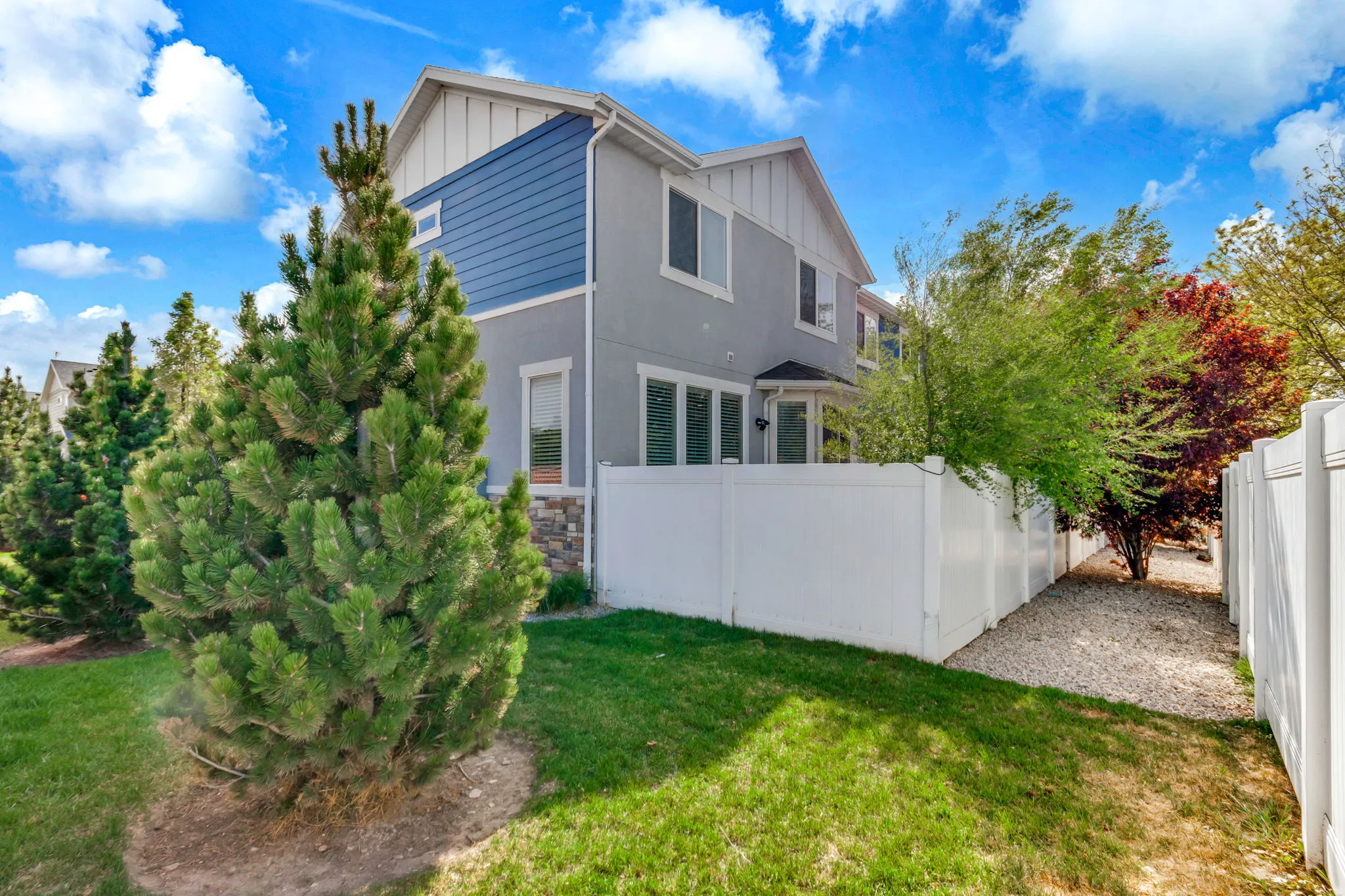 Back of property featuring board and batten siding, stone siding, and stucco siding