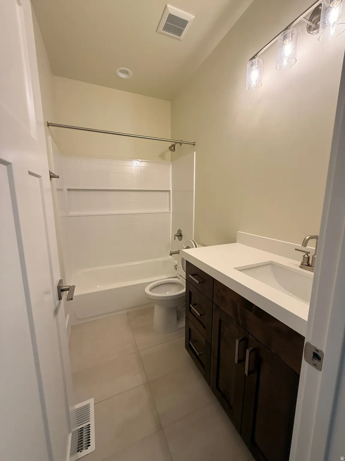 Bathroom featuring a dark wood-finish vanity with a white countertop, undermount sink, and brushed nickel fixtures