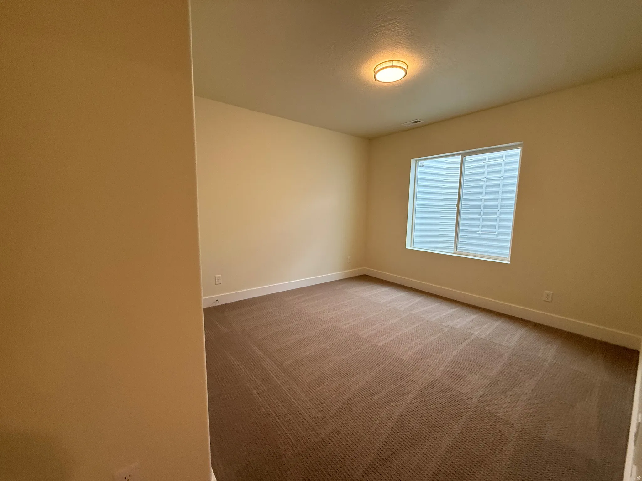 Recessed window with horizontal blinds, flush mount ceiling light fixture, and neutral carpeting