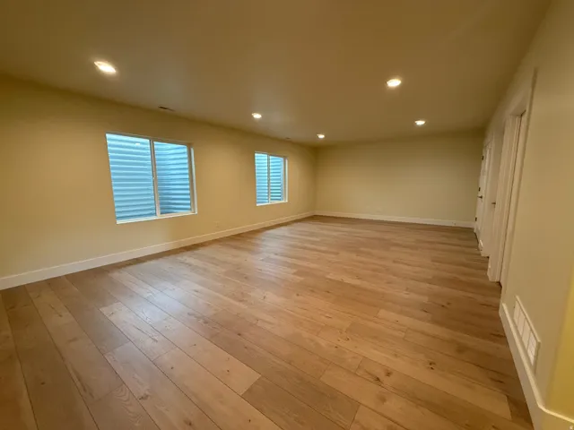 Spacious room featuring wood-finish flooring, recessed lighting, and two windows