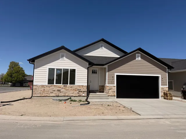 View of front of house with a garage, driveway, and stone siding