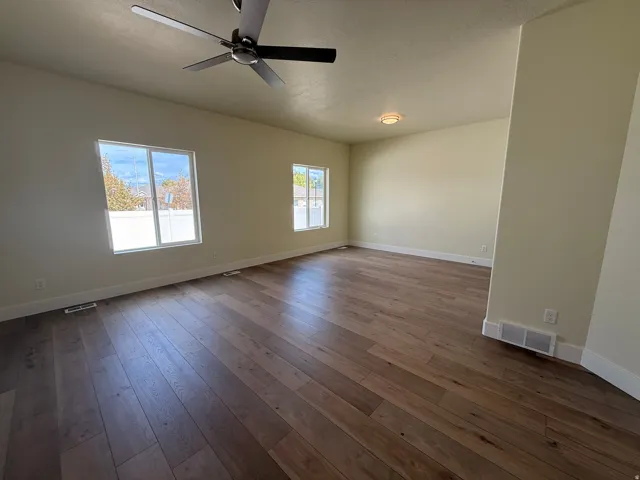 Spacious interior with wood-finish flooring, multiple windows, a ceiling fan, and a flush-mount light fixture